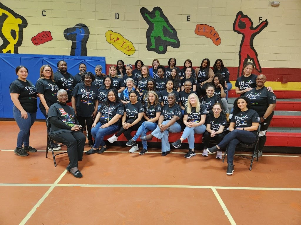 Image shows several of the teachers from the Fred W. Martin Center for the Arts sitting and standing in a gymnasium.