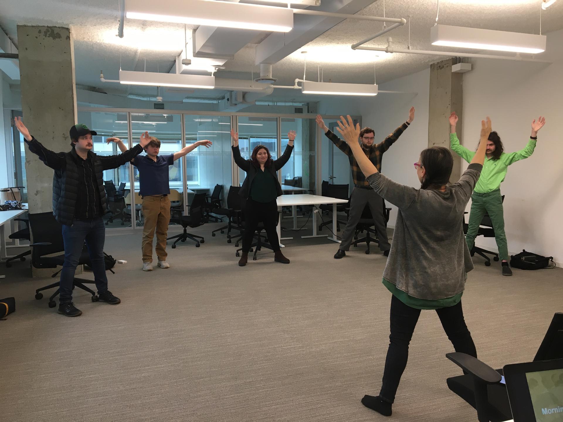 Image shows our five interns and yoga instructor practicing yoga with their hands and legs spread out.